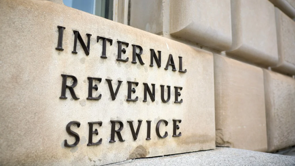 Close-up of raised metal INTERNAL REVENUE SERVICE lettering on a light stone building facade